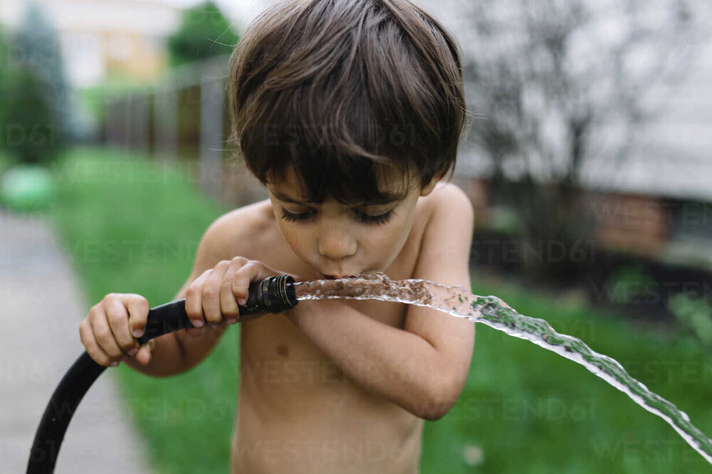 close-up-of-bare-chested-young-boy-with-brown-hair-drinking-water-from-a-hose-MINF05214.jpg